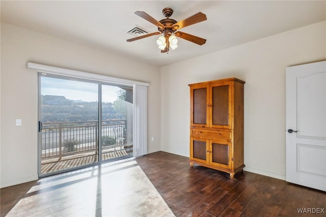 spare room featuring a ceiling fan, visible vents, dark wood finished floors, and baseboards