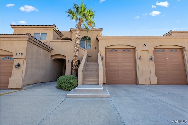 view of front of property with an attached garage, concrete driveway, a tiled roof, stairway, and stucco siding