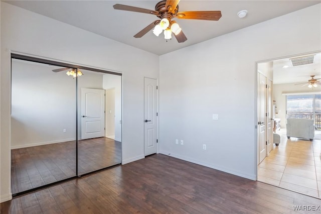 unfurnished bedroom featuring ceiling fan, wood finished floors, visible vents, and baseboards