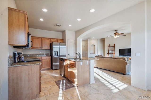 kitchen with a center island with sink, visible vents, arched walkways, open floor plan, and stainless steel appliances