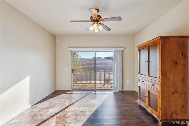 interior space with ceiling fan, dark wood-style flooring, and baseboards