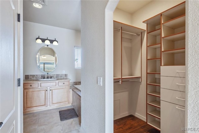 bathroom with a spacious closet, vanity, and tile patterned floors