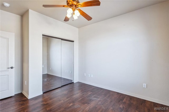 unfurnished bedroom featuring a closet, dark wood-style flooring, baseboards, and a ceiling fan