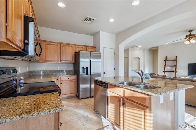 kitchen featuring a center island with sink, visible vents, light stone counters, stainless steel appliances, and a sink