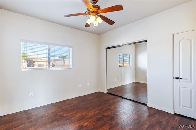 unfurnished bedroom with dark wood-style floors, a closet, multiple windows, and ceiling fan