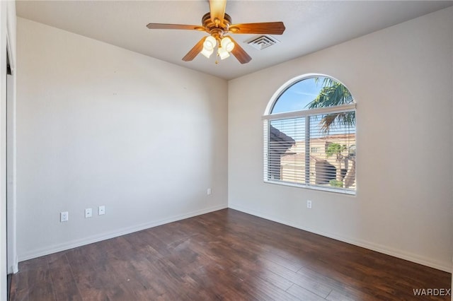 spare room with baseboards, visible vents, dark wood finished floors, and a ceiling fan