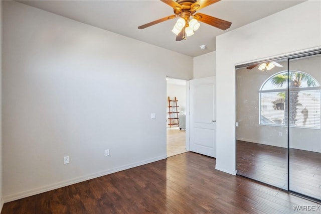 unfurnished bedroom with ceiling fan, a closet, baseboards, and dark wood-style flooring