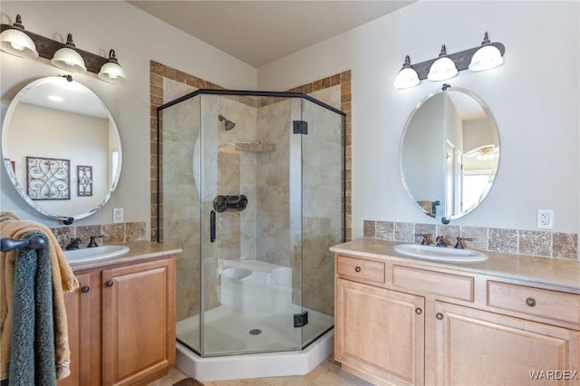 full bath with a stall shower, two vanities, and a sink