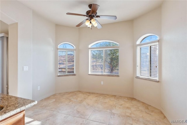 unfurnished room with ceiling fan and baseboards