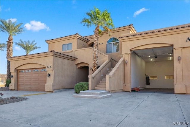 mediterranean / spanish-style home featuring an attached garage, stairway, concrete driveway, and stucco siding