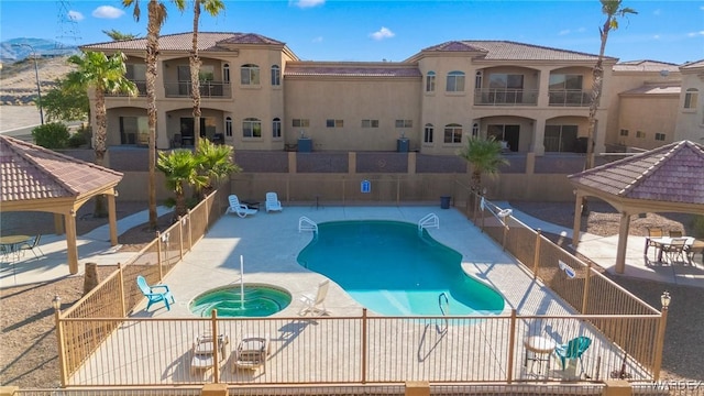 community pool featuring a gazebo, a patio, a community hot tub, and fence