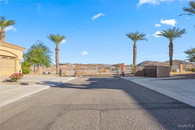 view of road featuring a residential view, a gated entry, curbs, a gate, and sidewalks