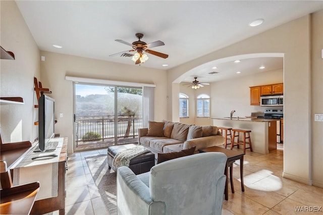 living room with a ceiling fan, arched walkways, light tile patterned flooring, and recessed lighting