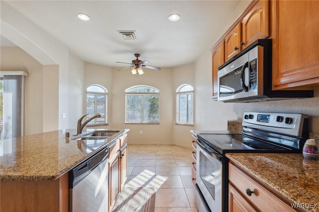 kitchen with a kitchen island with sink, a sink, visible vents, appliances with stainless steel finishes, and brown cabinetry