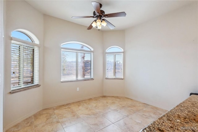 empty room with ceiling fan and baseboards