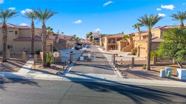 view of road with a gate, sidewalks, a gated entry, a residential view, and curbs