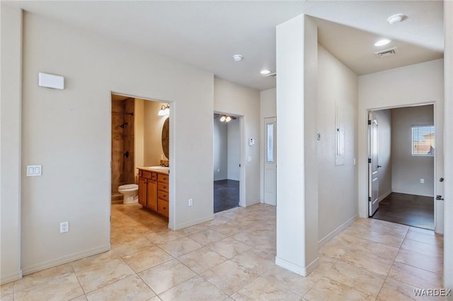 interior space with baseboards, visible vents, a sink, and ensuite bathroom