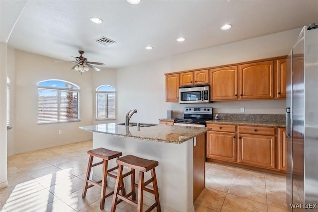 kitchen featuring stainless steel appliances, a sink, visible vents, a kitchen breakfast bar, and a center island with sink