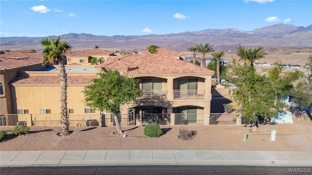 exterior space with fence, a tile roof, a mountain view, and stucco siding