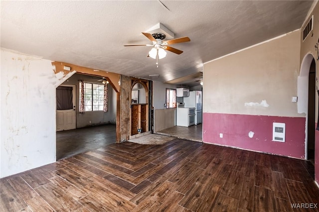unfurnished living room with visible vents, a ceiling fan, wood finished floors, and arched walkways