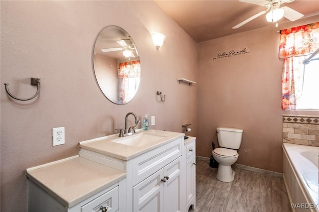 full bath featuring a ceiling fan, wood finished floors, a bath, vanity, and toilet