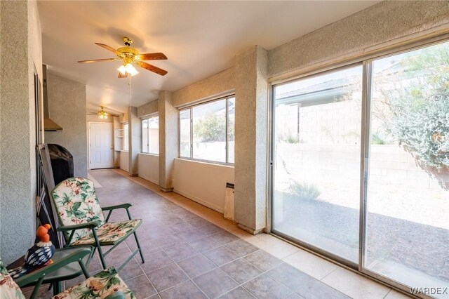 unfurnished sunroom featuring a ceiling fan