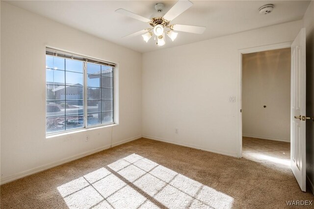 empty room featuring light carpet, baseboards, and a ceiling fan