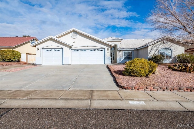 view of front of property featuring concrete driveway, an attached garage, a tile roof, and stucco siding