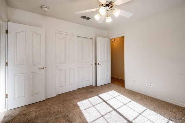 unfurnished bedroom with a closet, visible vents, a ceiling fan, light carpet, and baseboards