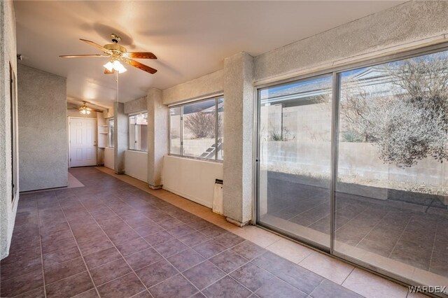 unfurnished sunroom with a ceiling fan