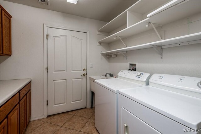 clothes washing area featuring light tile patterned floors, separate washer and dryer, visible vents, and cabinet space