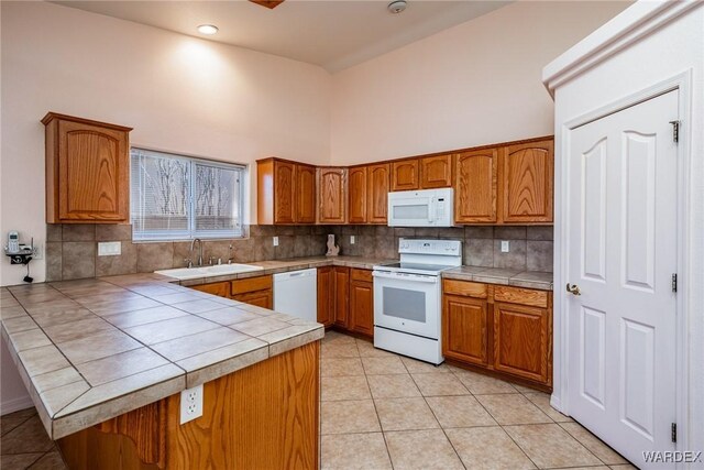 kitchen with tile countertops, white appliances, brown cabinetry, and a sink