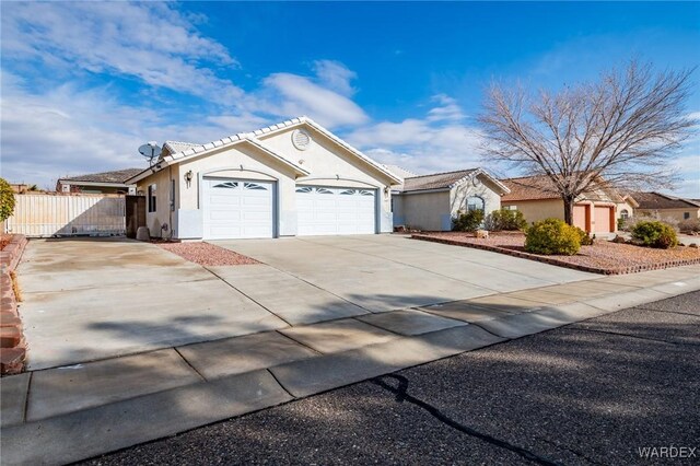 single story home featuring a tile roof, stucco siding, an attached garage, fence, and driveway