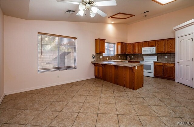 kitchen with brown cabinets, light countertops, visible vents, white appliances, and a peninsula