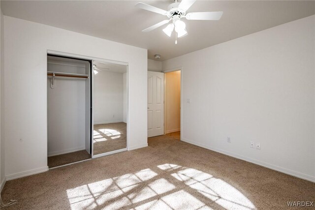 unfurnished bedroom featuring a closet, light carpet, ceiling fan, and baseboards