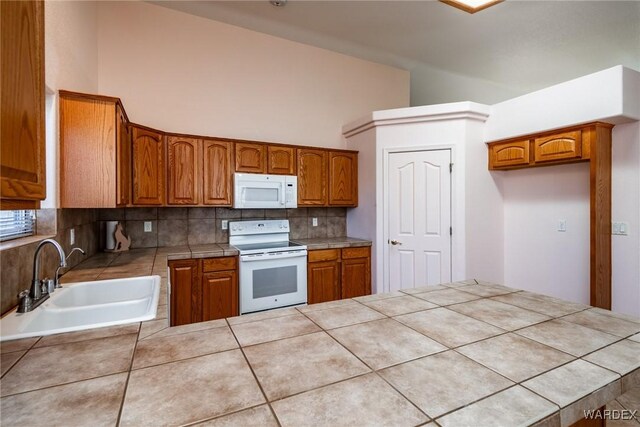 kitchen featuring tile countertops, white appliances, brown cabinetry, and a sink