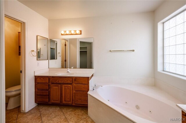 bathroom with a jetted tub, tile patterned floors, toilet, and vanity