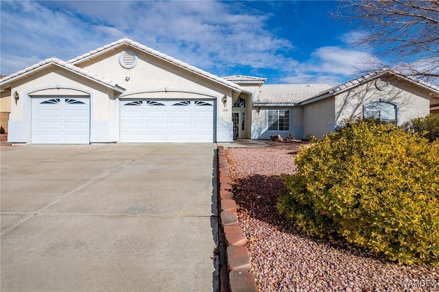 single story home with driveway, an attached garage, a tiled roof, and stucco siding