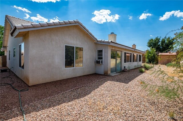 rear view of property with cooling unit, fence, a tiled roof, stucco siding, and a chimney