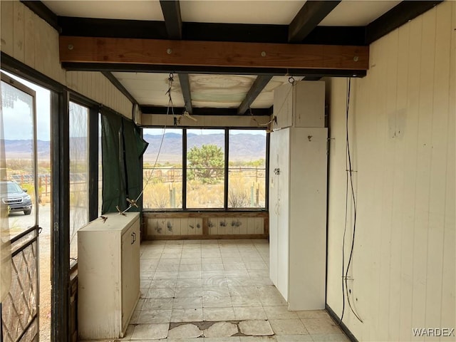 unfurnished sunroom with beam ceiling and a mountain view