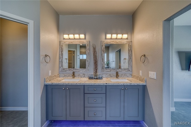 bathroom featuring double vanity, baseboards, and a sink