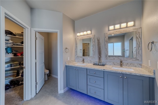 full bath featuring a sink, toilet, double vanity, and a spacious closet