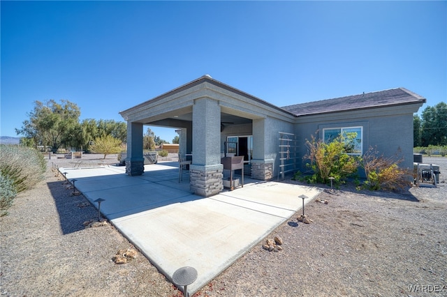 view of front of property with a patio, stone siding, and stucco siding