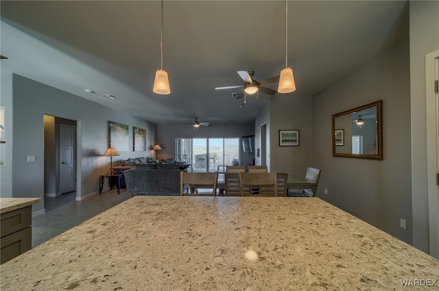 kitchen featuring baseboards, light stone countertops, pendant lighting, and open floor plan