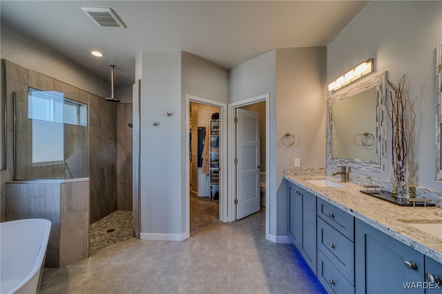 full bath featuring visible vents, a sink, double vanity, a freestanding bath, and walk in shower