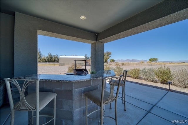 view of patio with outdoor dry bar, a mountain view, and fence