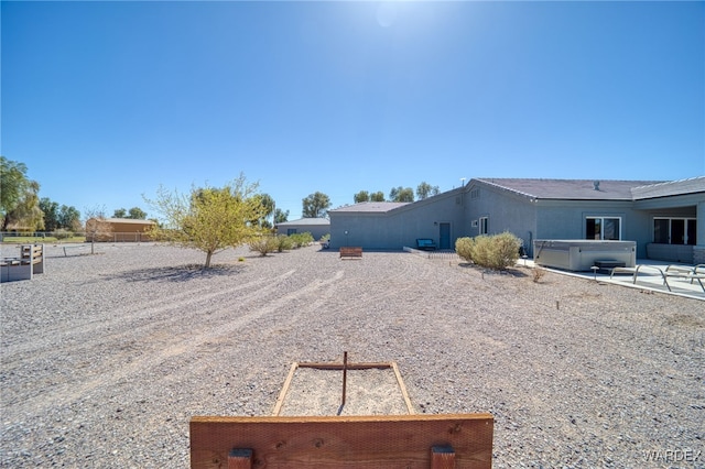 view of property exterior with a patio and a hot tub