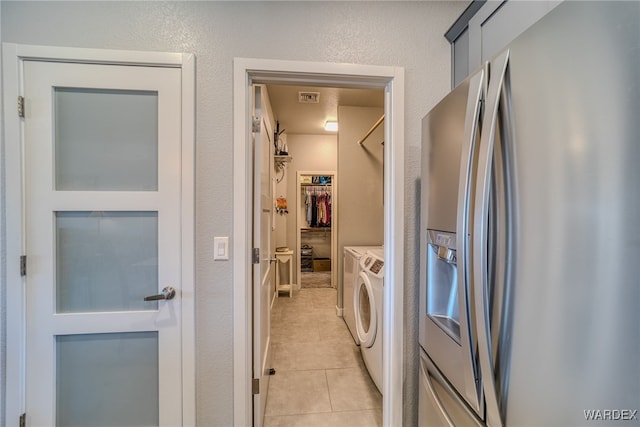 laundry area with washer and clothes dryer, visible vents, light tile patterned floors, and a textured wall