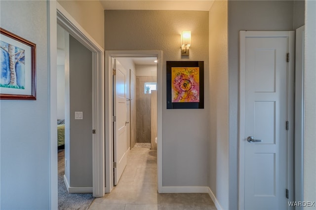 hallway with light tile patterned flooring and baseboards