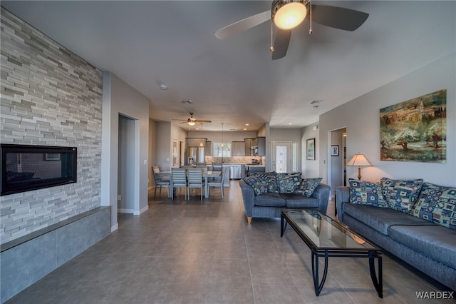 living room featuring a ceiling fan, baseboards, and dark tile patterned flooring